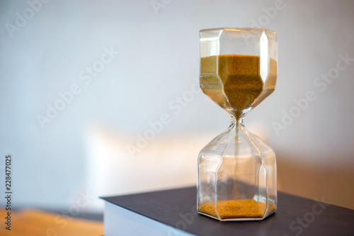 Hourglass and old book with blurred background. Leave copy space for adding text.