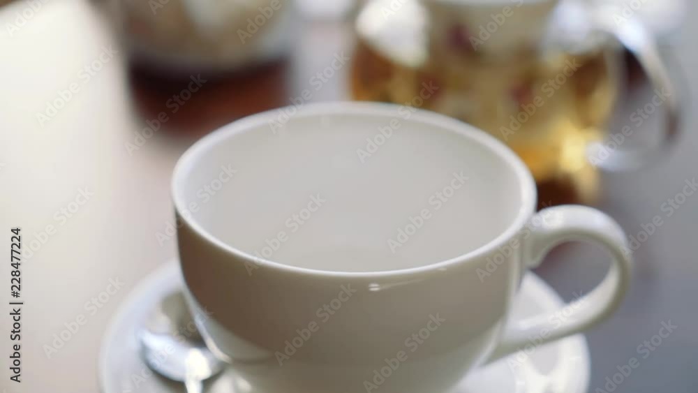 The hand of the girl puts sugar raffinate in a cup for tea. The hand of the girl puts sugar raffinate in a cup for tea.
