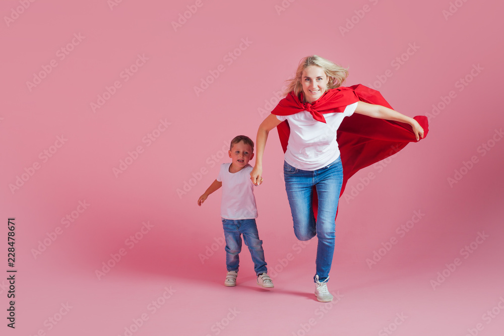 super mom and her son run forward. Fun family, a young blond woman in a red Cape as superhero super mom and her son run forward. Fun family, a young blond woman in a red Cape as superhero