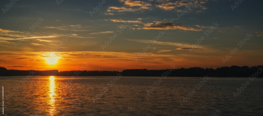 Toned photo of sunset over the lake with forest on the opposite bank