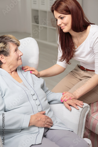 Friendly caregiver taking care of smiling senior woman during meeting at home