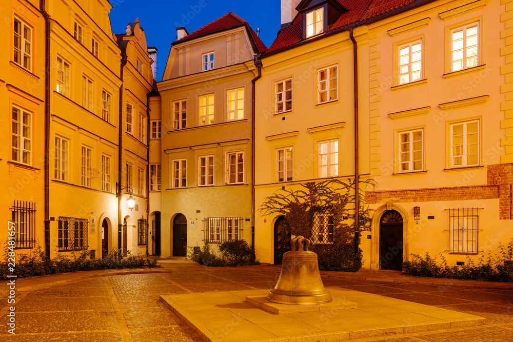 The wishing Bell and old townhouses in Kanonia Square in Warsaw at Night.
