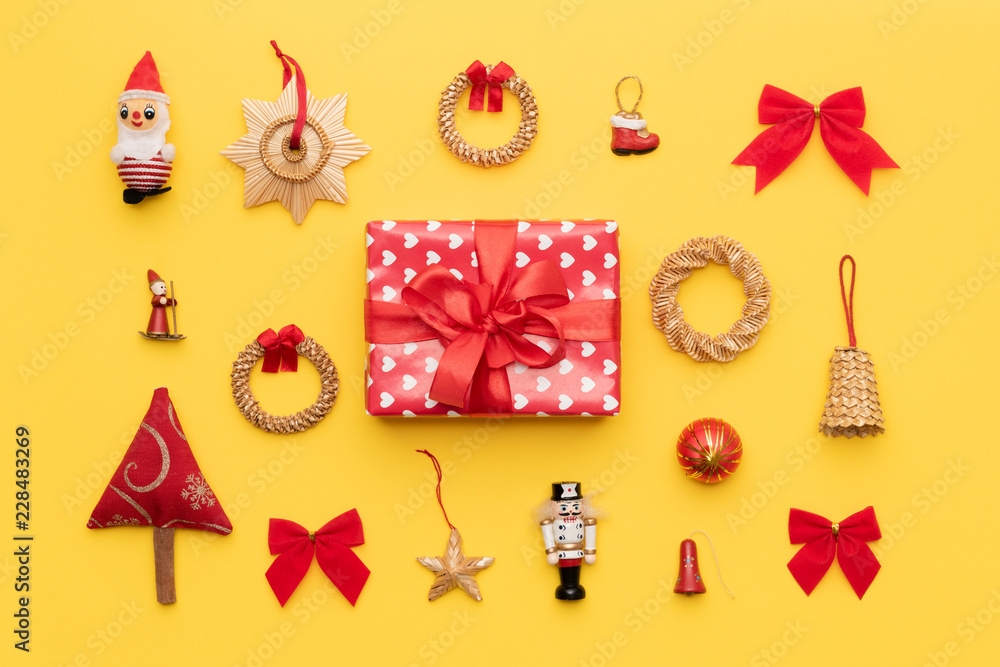 Red christmas gift and many retro christmas ornaments isolated on bright yellow background. Christmas composition.