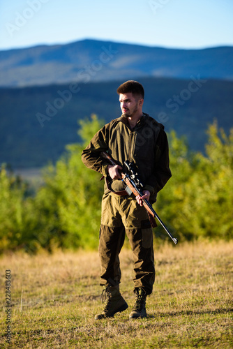 Hunter khaki clothes ready to hunt hold gun mountains background. Hunter with rifle looking for animal. Hunting shooting trophy. Mental preparation for hunting individual process. Man rifle for hunt