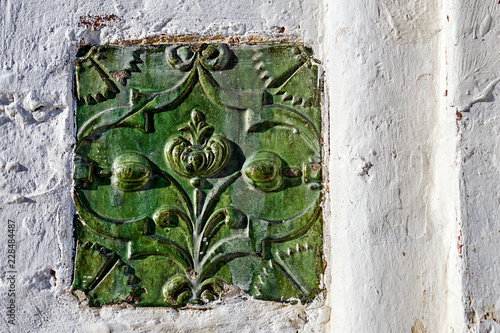 Ancient ceramic tile with a fairy flower image in the wall of the Joseph-Volotsky monastery in Russia