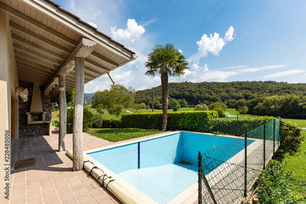 Villa with pool and surrounded by green lawn on a summer day Villa with pool and surrounded by green lawn on a summer day