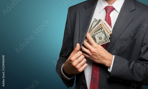 Pocketing company money. businessman placing money into photo
