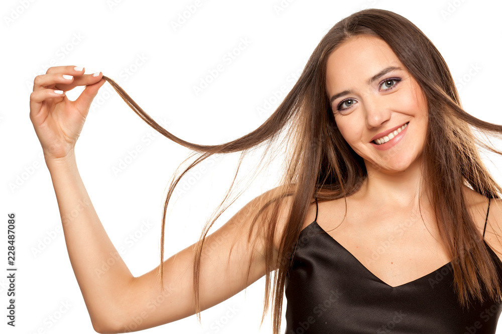 Happy attractive girl showing the length of her hair on white background