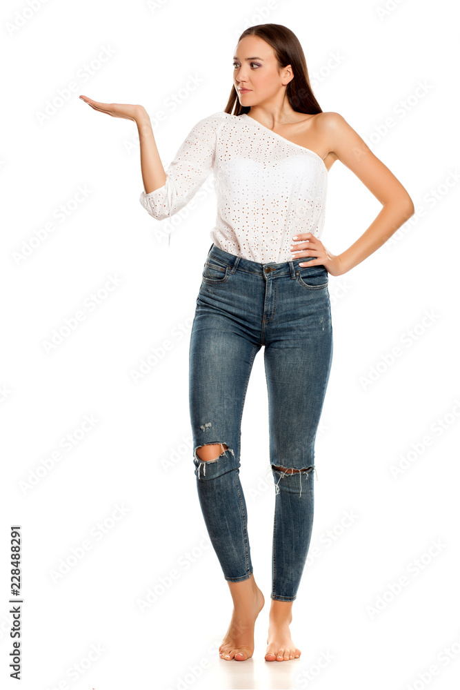 Barefoot young beautiful girl in jeans presenting something on white background Barefoot young beautiful girl in jeans presenting something on white background