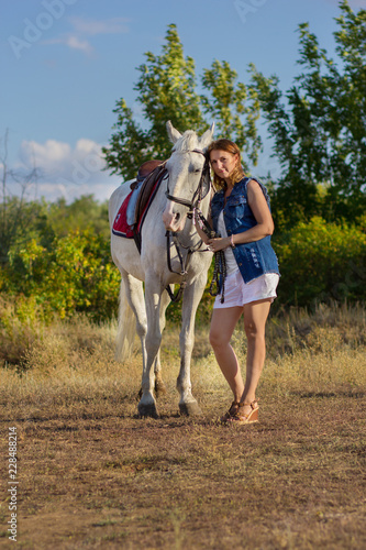 The girl in shorts embraces a white horse © borisenkoket