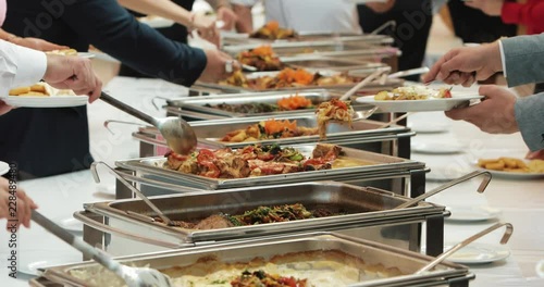 People group catering buffet food indoor in luxury restaurant with meat colorful fruits and vegetables. Close up. Banquet, lunch, bad nutrition, gluttony concept