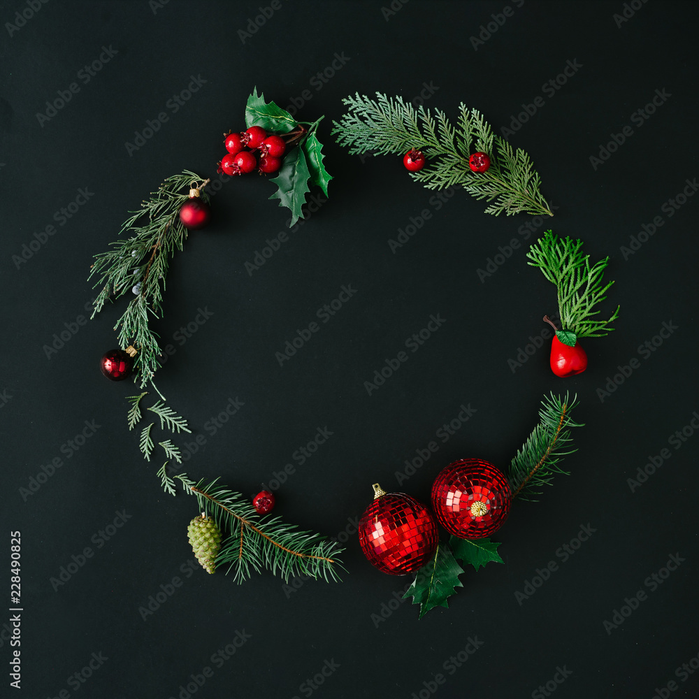Creative Christmas round frame or wreath made with natural winter evergreen tree branches and red berries. Flat lay. Nature concept.