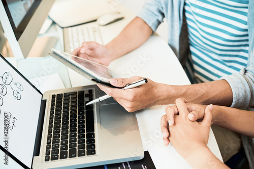 Faceless shot from above of professional modern workers using tablet in team while working in office