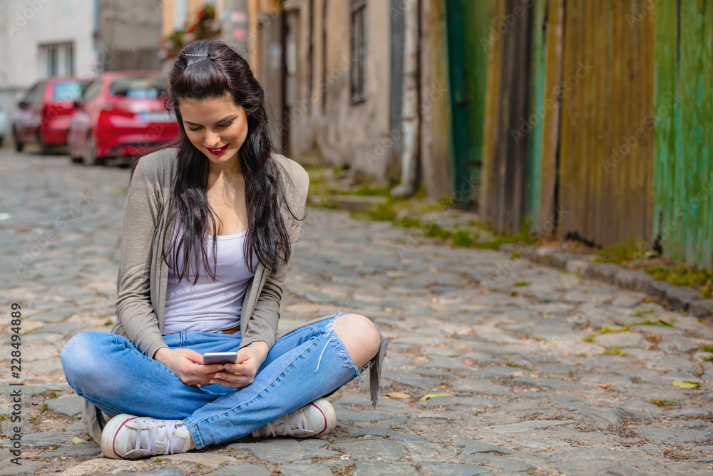 Cute young woman using cellphone in urban surroundings. Cute young woman using cellphone in urban surroundings.