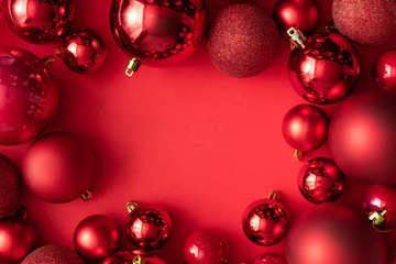 Red Christmas baubles decoration on red background with copy space. New Year greeting card. Minimal style.  Flat lay.
