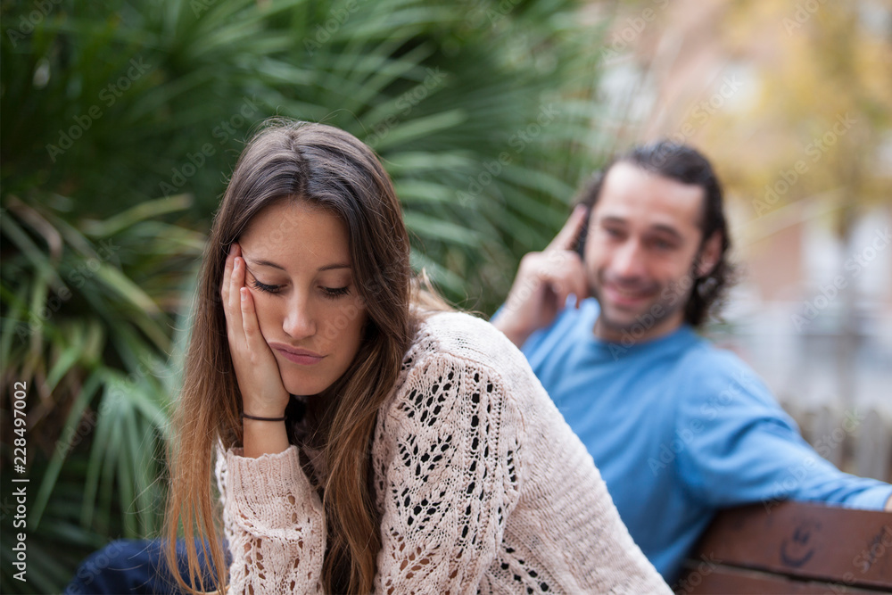 Fototapeta premium Sad wife with indifferent husband using phone. Relationship problems concept