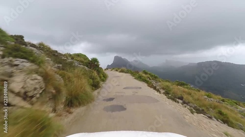 
car drives on a narrow dangerous mountain road in high mountains after heavy rain - POV - Point of view driving,camera on gimbal outside the vehicle.