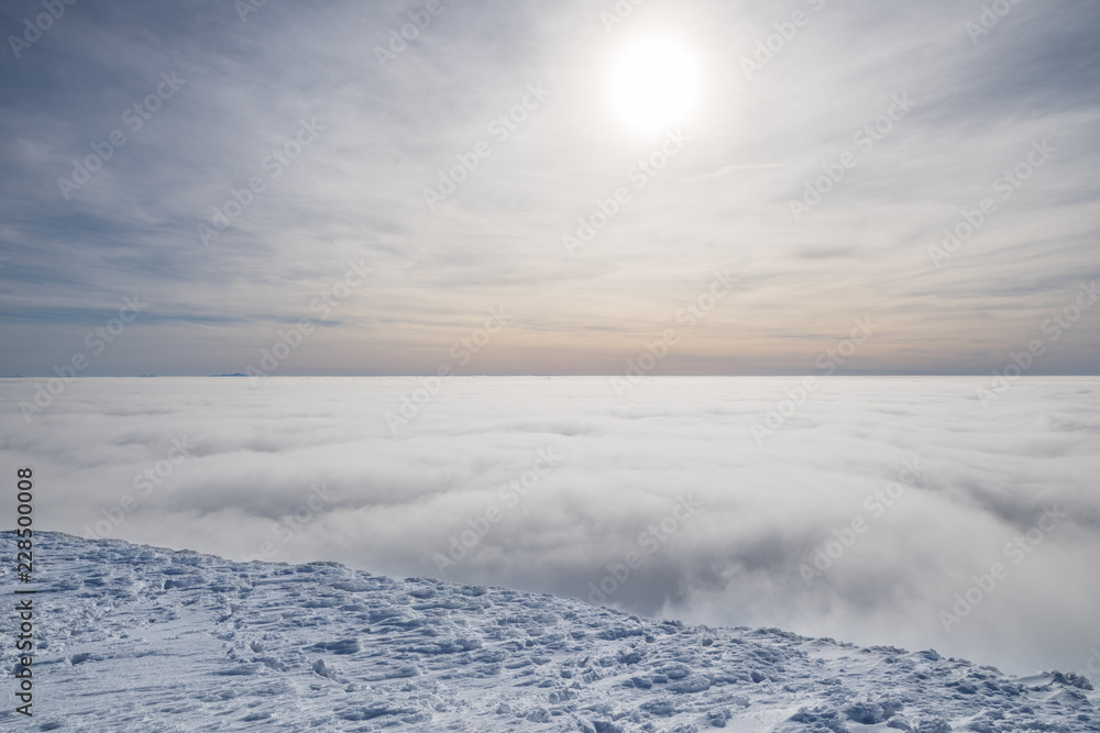 Fresh sparkling snow cover on mountain tops. Cloudy sky at the background.