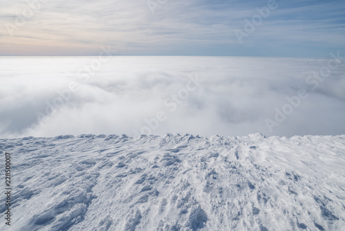 Mountain tops covered with snow above the white heavy clouds.