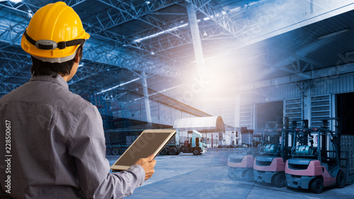 Engineer manager Wearing hard Hat using tablet check and control for workers with warehouse logistics. Industry 4.0 concept.