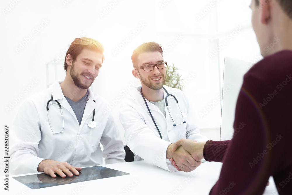 Smiling doctor at the clinic giving an handshake to his patient Smiling doctor at the clinic giving an handshake to his patient