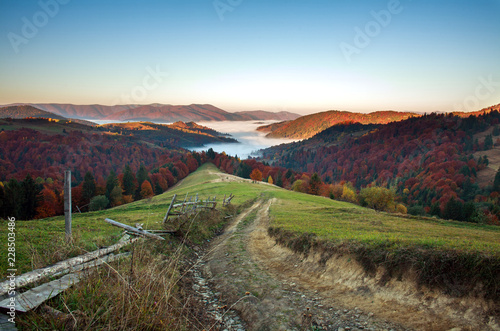 Rural road trail in autumn mountains in fog at sunrise beauty in nature