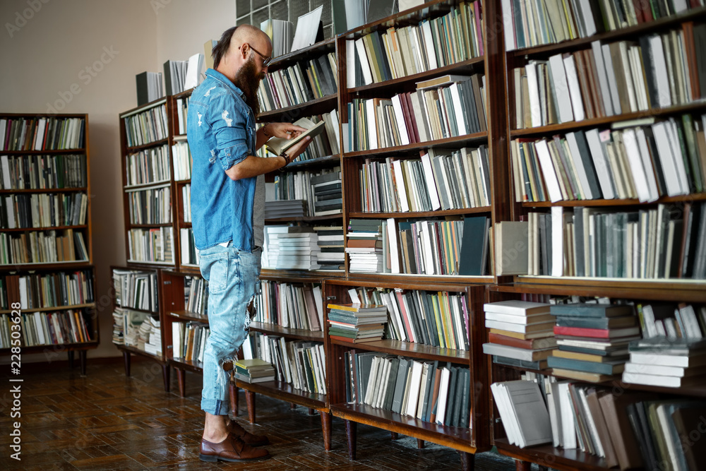 Full length portrait of stylish bearded man reading book Full length portrait of stylish bearded man reading book