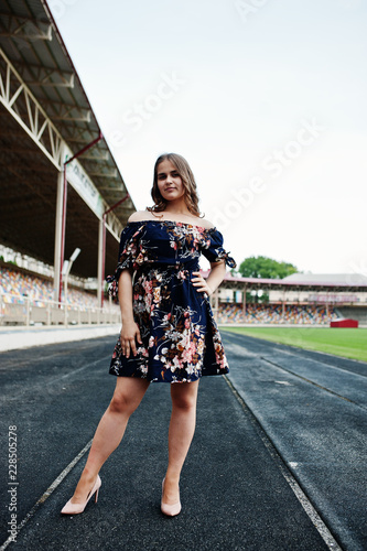Portrait of a fabulous girl in dress and high heels on the track at the stadium.