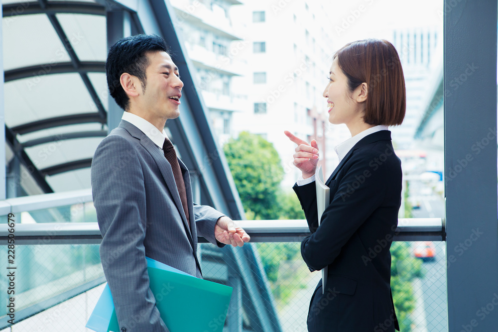 屋外で話すスーツ姿の男女 屋外で話すスーツ姿の男女
