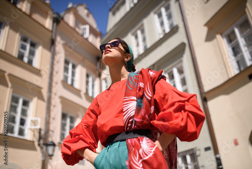 Portrait of a young woman in red clothes posing on the background of old building in Warsaw, Poland. Fashion concept