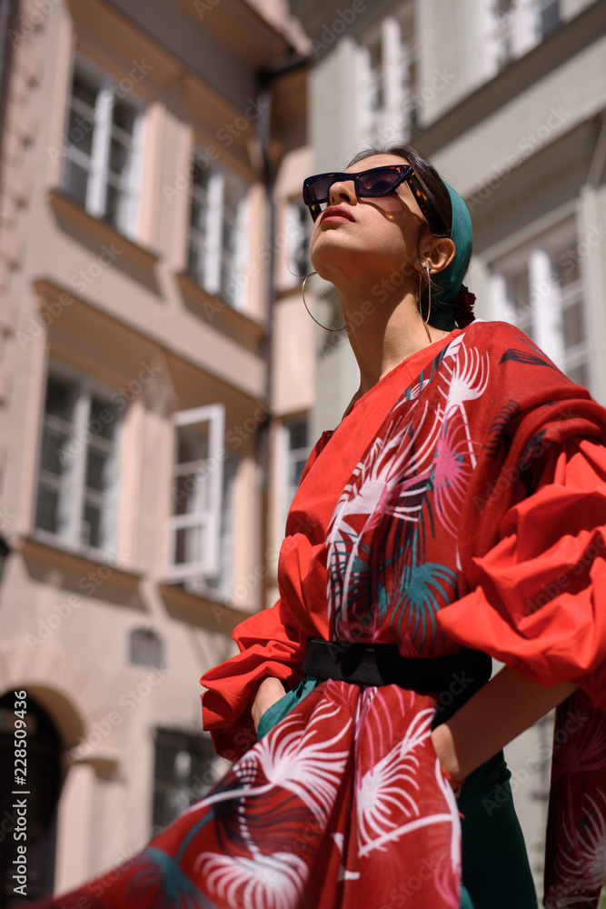 Portrait of a young woman in red clothes posing on the background of old building. Fashion concept