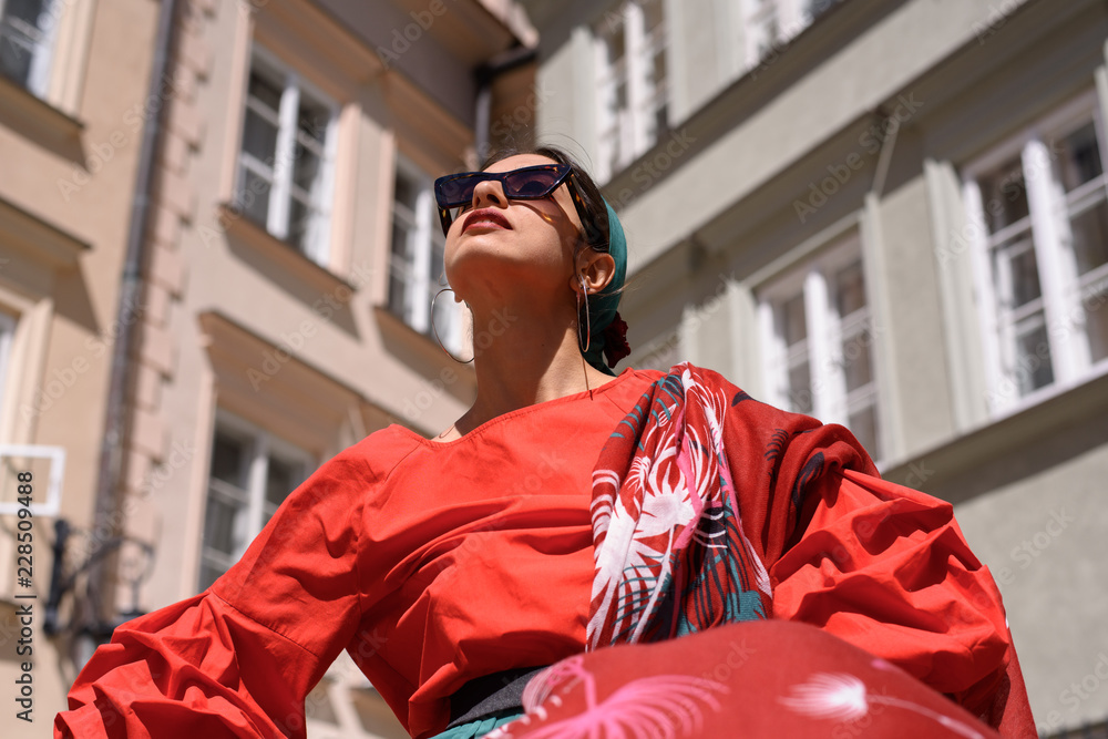 Fototapeta premium Fashion portrait of young spanish woman in sunglasses. Fashion latin look. Woman walking in old town