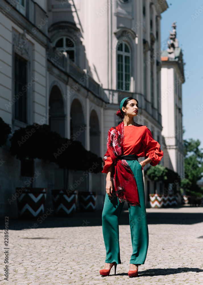 Portrait of a young woman in red clothes posing on the background of old building. Fashion concept
