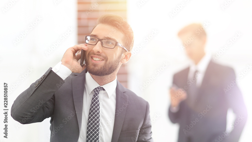 Confident young man talking on phone in office Confident young man talking on phone in office