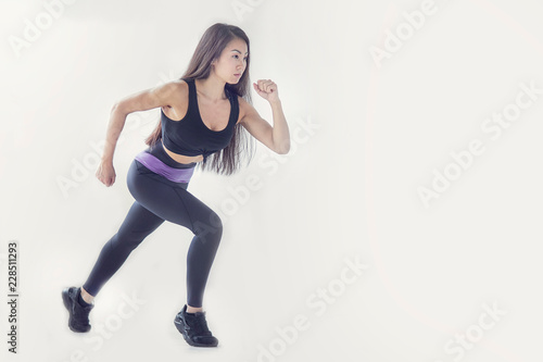 Side view full length portrait of a young fitness woman running isolated over gray background © yavdat
