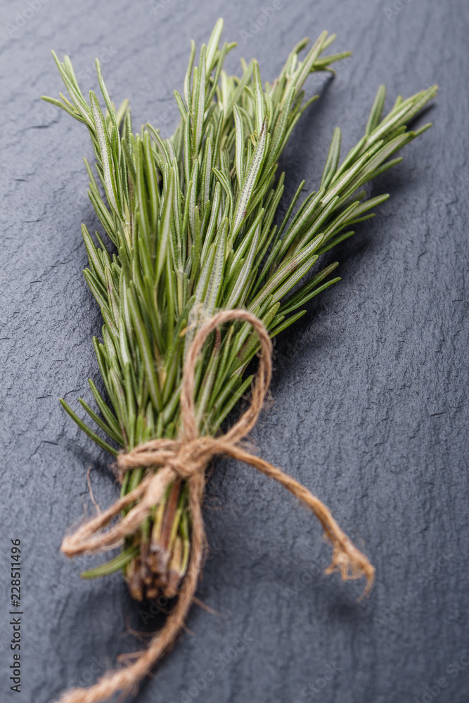 Rosemary essential oil on dark stone background Rosemary essential oil on dark stone background