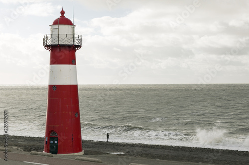 An idyllic view towards a lighthouse, human vs nature, small vs big, creation vs destruction