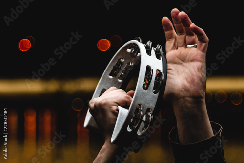Fototapeta Man playing the tambourine on the background of night lights