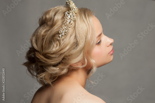 Beautiful blond girl in the image of a bride with a tiara in her hair. Picture taken in the studio on a gray background. Beauty baby face. Wedding image.