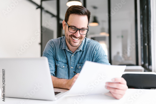 Handsome young smiling businessman working with documents. photo
