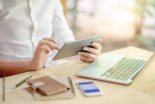 Male businessman hands using tablet application touch screen on digital tablet with laptop computer and smartphone on the table. Urban lifestyle with electronic gadget concepts