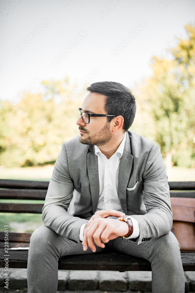 Portrait of a young businessman sitting on the bench, looking away. Portrait of a young businessman sitting on the bench, looking away.