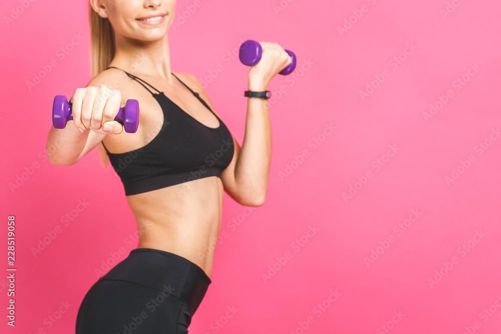 Sporty woman does the exercises with dumbbells. Photo of sporty woman in sportswear on white background. Strength and motivation. Isolated over pink. Sporty woman does the exercises with dumbbells. Photo of sporty woman in sportswear on white background. Strength and motivation. Isolated over pink.