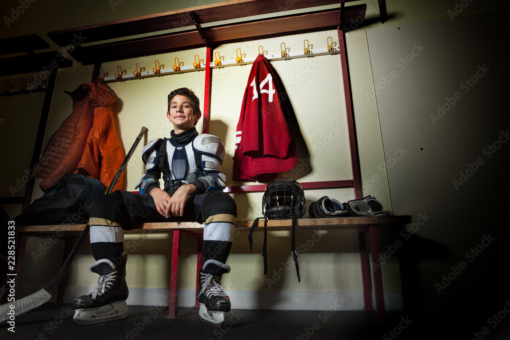 Fototapeta premium Happy boy sitting in ice hockey dressing room