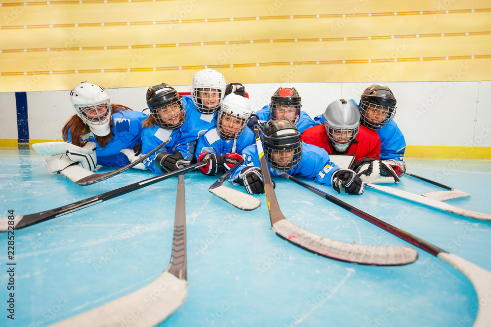 Fototapeta premium Happy hockey team laying on ice rink at stadium