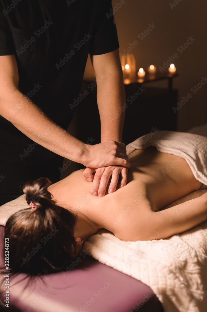 Fototapeta premium Close up Male manual worker doing spa massage to a young girl in a dark room