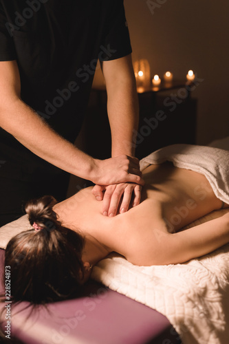 Close up Male manual worker doing spa massage to a young girl in a dark room