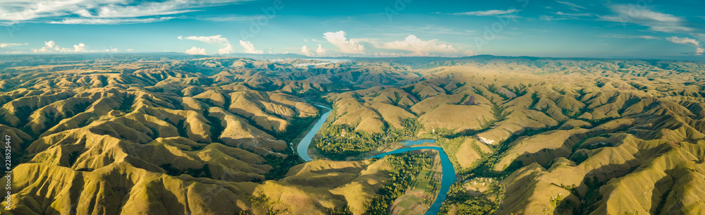 Panoramic view river, hills. Aerial drone shot. Indonesia. Spectacular landscape of Sumba island. Blue sky with white clouds . Beauty of wild untouched nature. - obrazy, fototapety, plakaty 