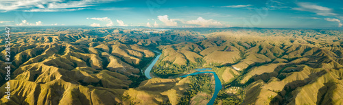 Panoramic view river, hills. Aerial drone shot. Indonesia. Spectacular landscape of Sumba island. Blue sky with white clouds . Beauty of wild untouched nature.