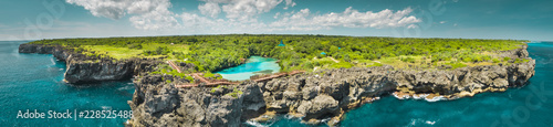 Aerial drone shot green-capped island, ocean. Panorama. Indonesia. Spectacular view from above Sumba island the plain with greens and pure lakes on the blue cloudy sky background. Indian ocean. photo